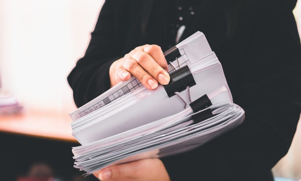 Woman Holding Stack of Paper Documents